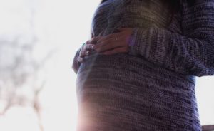 Pregnant Woman Wearing Marled Gray Sweater Touching Her Stomach (source: Pexels)
