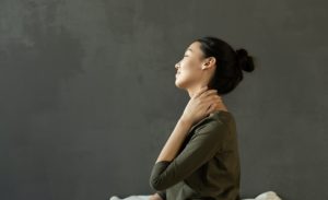 woman sitting down holding sore neck
